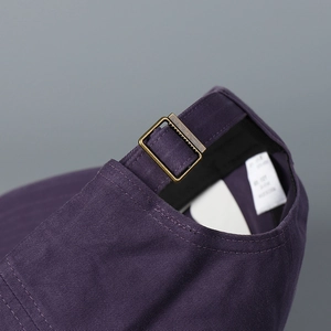 Macro shot of dark purple baseball cap featuring vintage brass adjustable metal buckle