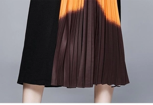 Détail de la jupe plissée en maille avec dégradé de couleurs noir, orange et café