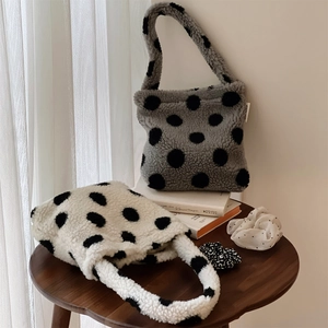 Sac à main en peluche à pois gris et blanc cassé sur une table en bois