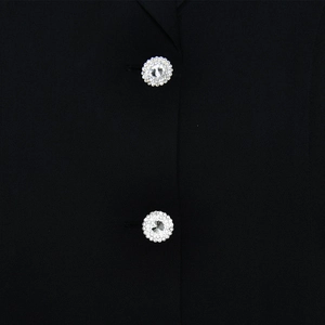 Gros plan de boutons argentés sertis de diamants sur le tissu noir de la robe