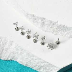 Detailed macro view of silver stainless steel labret studs with zircon flowers and stars