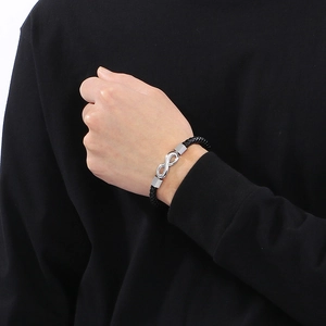 Detailed view of black braided leather bracelet featuring a silver infinity charm for men