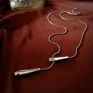 Close-up of silver snake chain with teardrop pendant on red velvet background