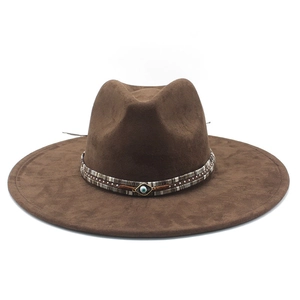 Detail of brown wool felt fedora featuring an ethnic woven band and evil eye metal charm