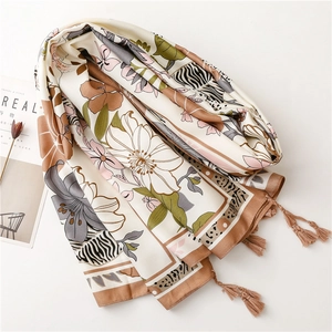 Close-up of silk scarf featuring floral and animal print patchwork with fringe tassels
