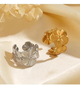Close-up of gold and silver flower open rings on soft fabric with dried floral accents