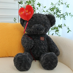 Dark grey teddy bear plush toy with red heart balloon in a cozy home setting