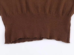 Detail shot of the ribbed hem on a brown knitted sweater showing high-quality fabric texture