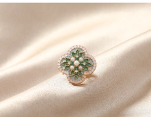 Macro shot of vintage flower brooch with light green enamel and faux pearls on silk