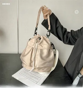 Close-up of beige nylon bucket bag featuring drawstring closure and metallic hardware