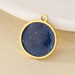 Macro shot of a round gold stainless steel charm with blue glitter starry sky resin inlay