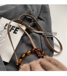 Detail of adjustable coffee shoulder strap with amber beads on plush bucket bag