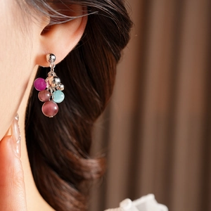 Detail of colorful beaded tassel earrings featuring opal-like stones on a side-view model