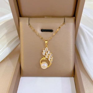 Détail du pendentif paon avec zircons en goutte et perle blanche sur chaîne dorée