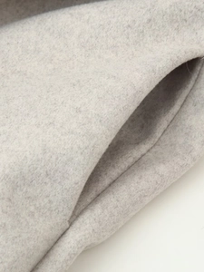 Detail of light gray wool coat featuring soft texture and a diagonal side pocket