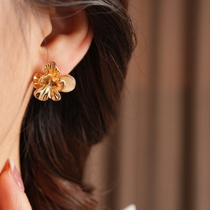 Close-up of golden vintage floral stud earring with cat-eye stone on a female model