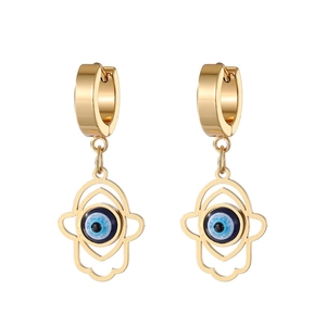 Detail of gold huggie earrings with hollow Hamsa Hand charms and blue Evil Eye accents
