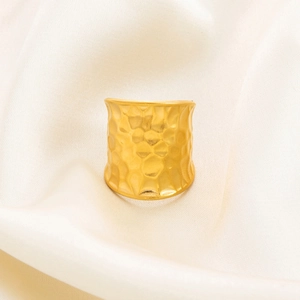 Detailed close-up of wide gold hammered texture ring on elegant beige silk fabric