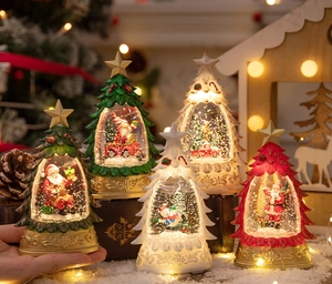 Close-up of assorted glowing Christmas tree snow globes with Santa and reindeer figurines