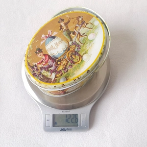 Detail of vintage Easter tin box showing weight on a scale and floral bunny patterns