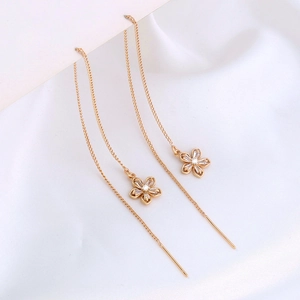 Detail of gold flower drop earrings with sparkling cubic zirconia on white silk