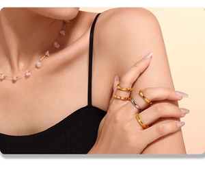 Vue détaillée de bagues dorées minimalistes superposées et d'un collier en pierre rose