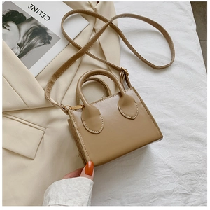 Detailed top view of a mini khaki leather handbag on a beige suit and white fabric