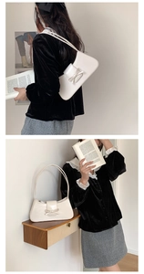 Detail of the white baguette shoulder bag featuring a sleek bow accent and PU leather finish