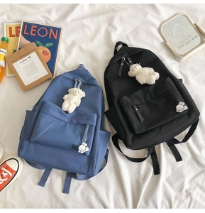Detail of waterproof nylon school bags in black and blue with plush bear charms