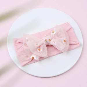 Detailed shot of pink mesh bow baby headband with white and yellow daisy embroidery