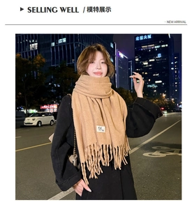 Detail of camel cashmere-feel scarf with tassels and brand tag in outdoor setting