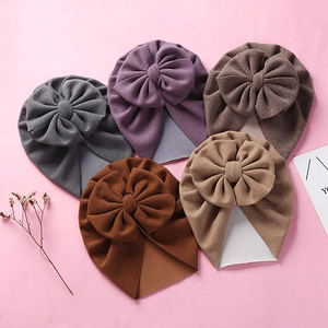 Flat lay of soft cashmere-style baby turban hats with large bows in five warm colors