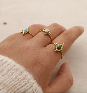 Close-up of gold stainless steel rings with turquoise and marble stones on model hand