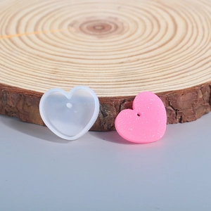Detailed view of heart silicone mold and pink glitter pendant on a wooden background