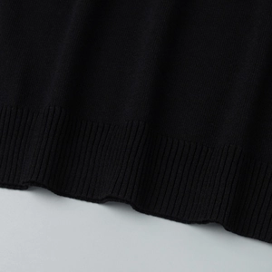 Vue détaillée du haut en tricot noir avec une finition soignée en bord-côte à la base