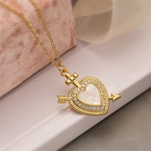 Gold heart necklace with cupid arrow and cross pendant on a pink velvet box