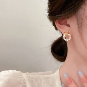 Detail of sweet bow knot pearl wreath earrings with sparkling rhinestones in gold