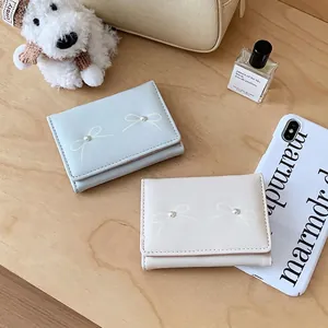 Short tri-fold wallet for women with bow and pearl detail in blue and beige PU leather