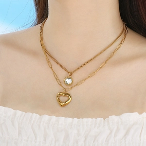 Zweilagige Goldkette mit Herz- und Kristallanhänger, getragen von einem Model