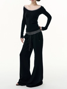 Detail of cable knit texture on black off-shoulder sweater and drawstring waist trousers