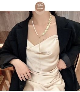 Dettaglio di una collana a Y dorata con perle naturali e foglie su una modella donna