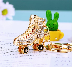 Macro view of gold roller skate keychain with white rhinestones and black enamel wheels