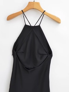Detail of cross-back straps on a black satin backless dress hanging on a wooden hanger