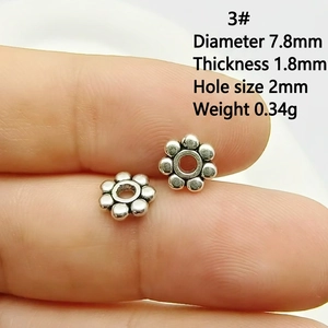 Gros plan de perles d'espacement flocon de neige en argent vintage de 7,8 mm sur le bout du doigt