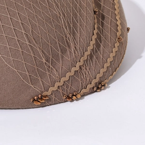 Close-up of brown wool felt beret featuring fine mesh veil and gold wave ribbon detail