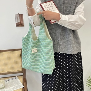 Close-up of green striped knit tote bag featuring a white minimalist brand label