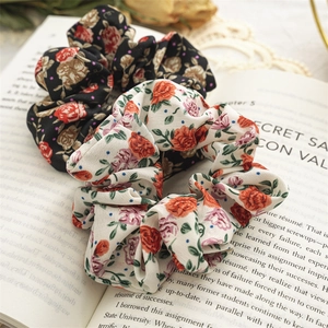 Two floral scrunchies in black and beige on an open book, French vintage style