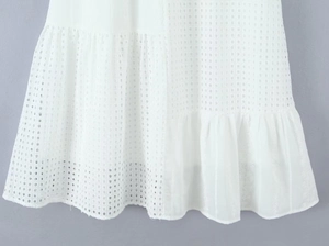 Dettaglio vestito bianco in cotone con intricato ricamo traforato e orlo in pizzo