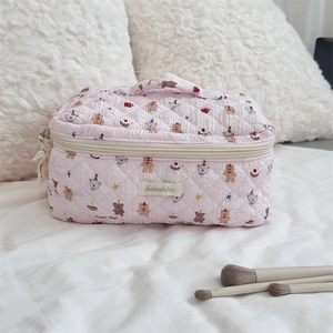 Detailed close-up of pink quilted cartoon cosmetic bag with cute bear and cake patterns