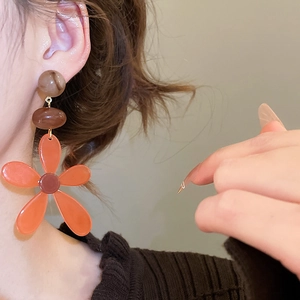 Detail of vintage resin flower drop earrings featuring warm amber petals and marbled beads